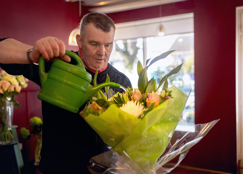 A florist pouring water in bouquet of flowers