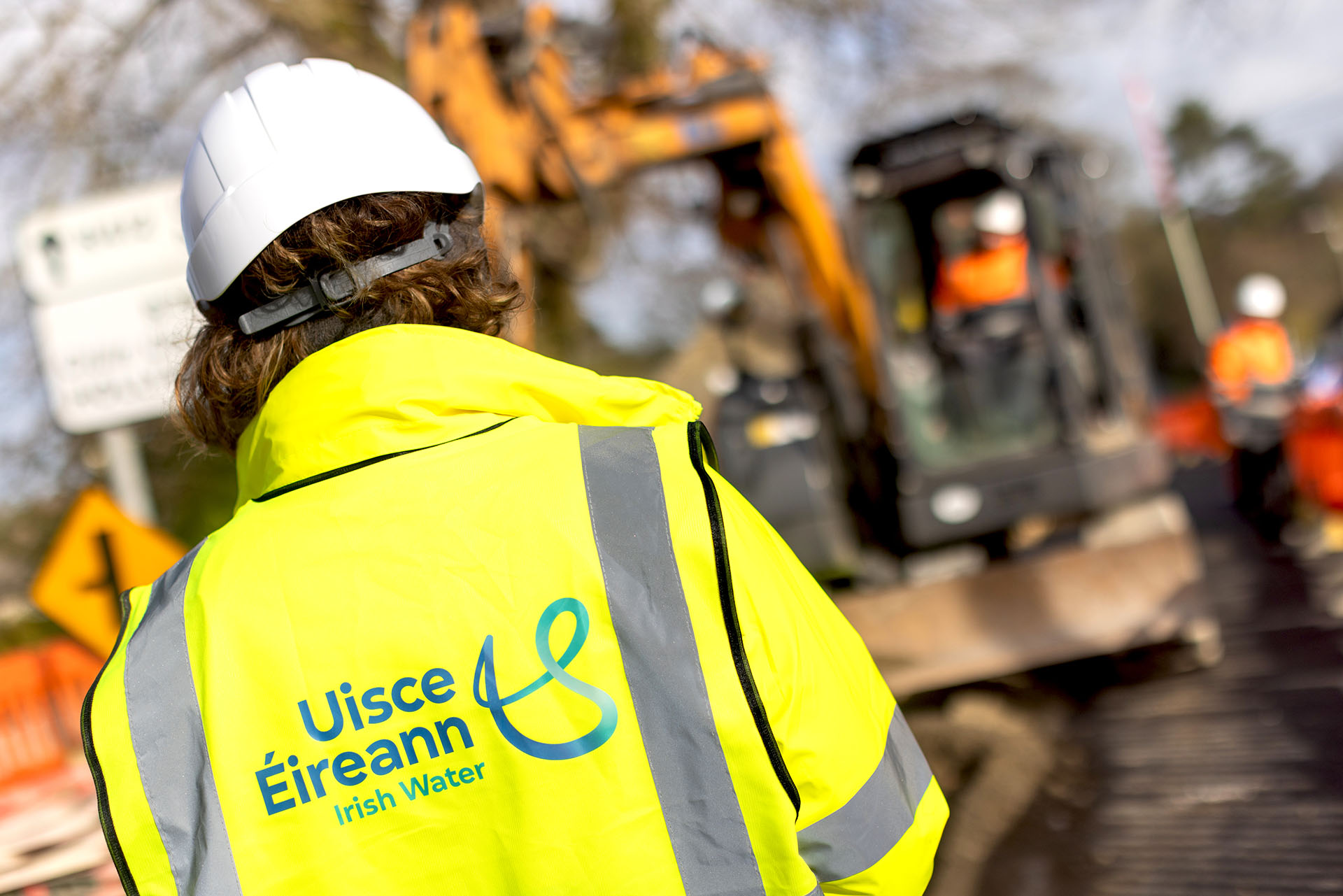 An Uisce Éireann engineer in front of a digger during road works