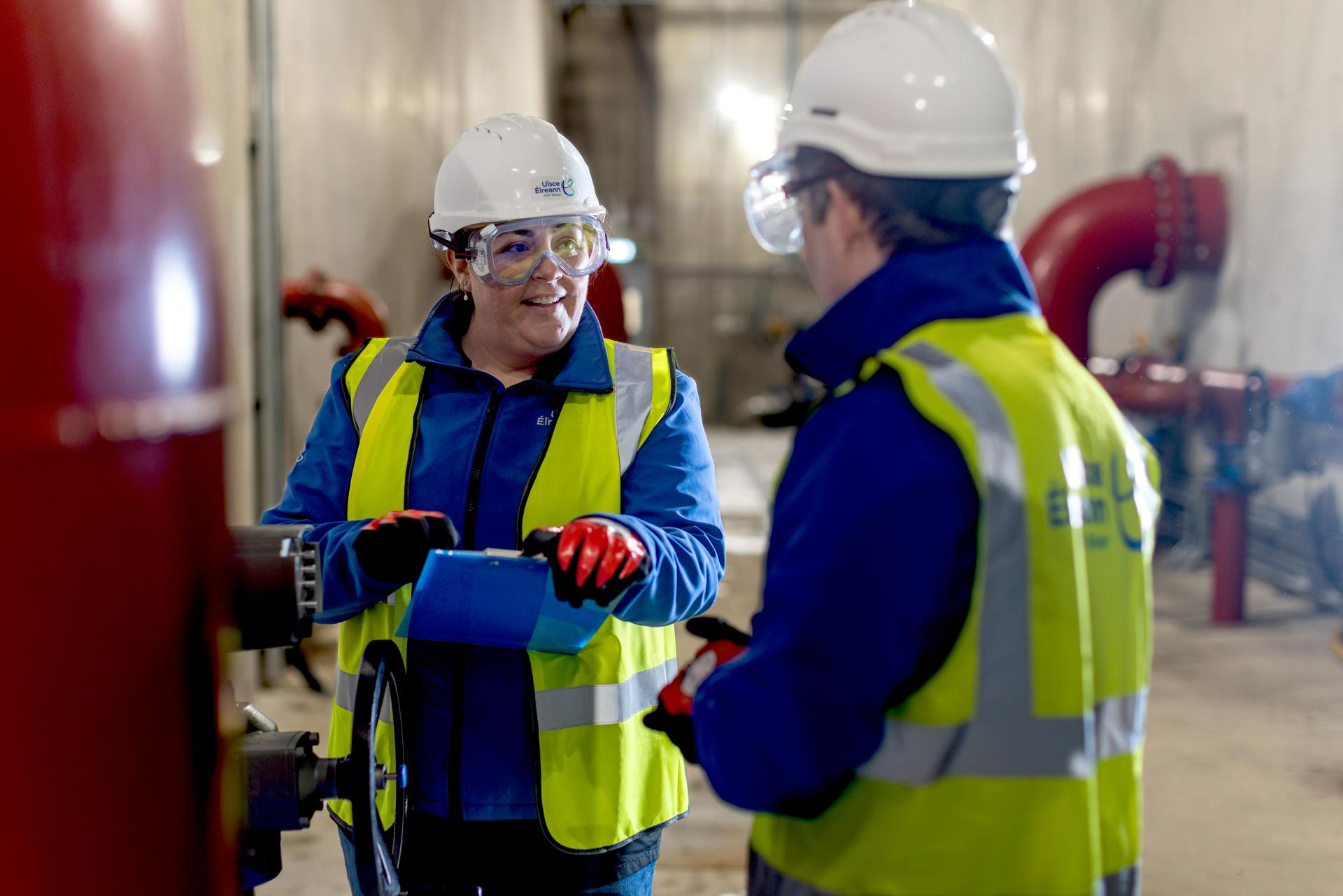Two Uisce Éireann engineers beside a large pipe with water valves
