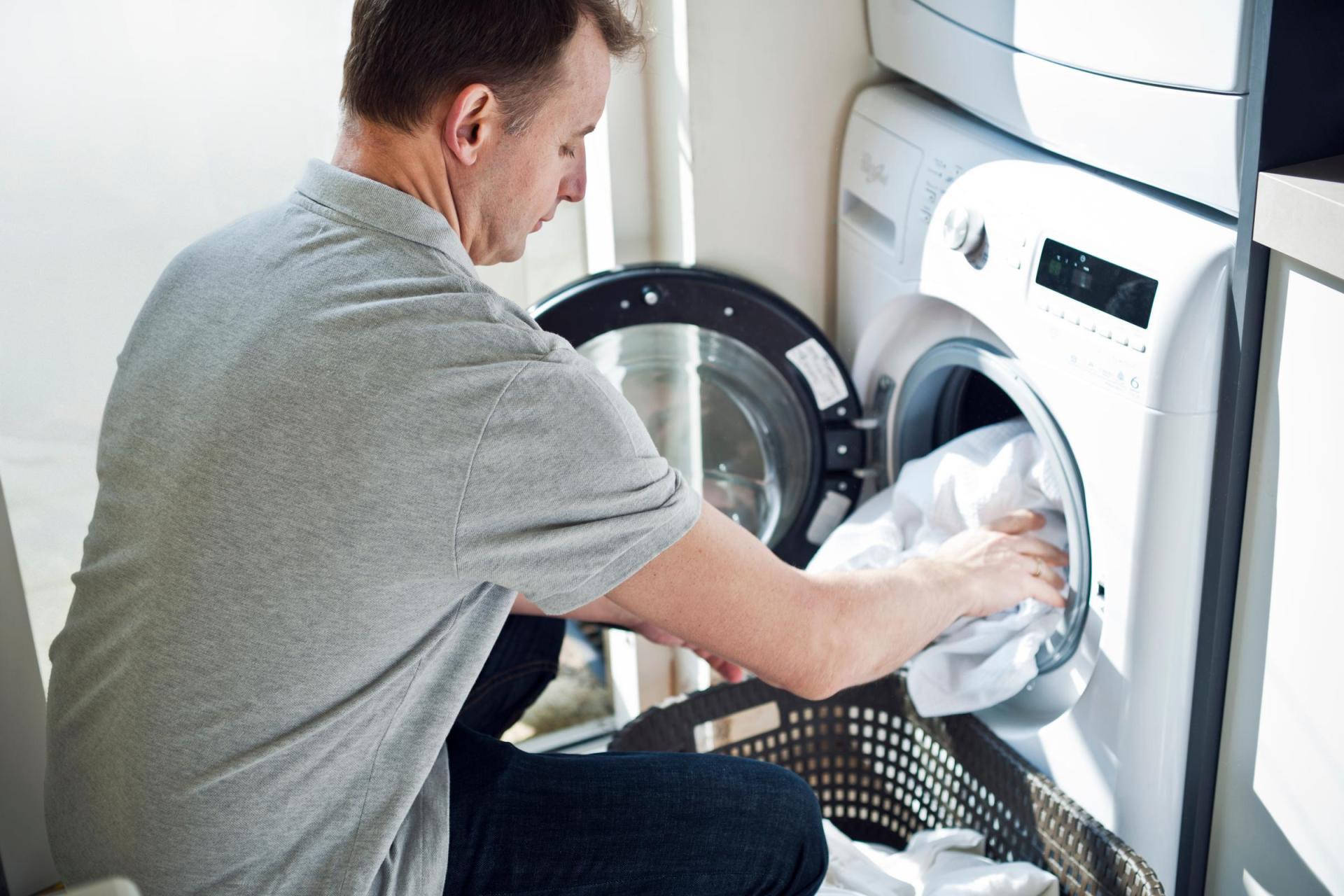 A man loading his washing machine with clothes
