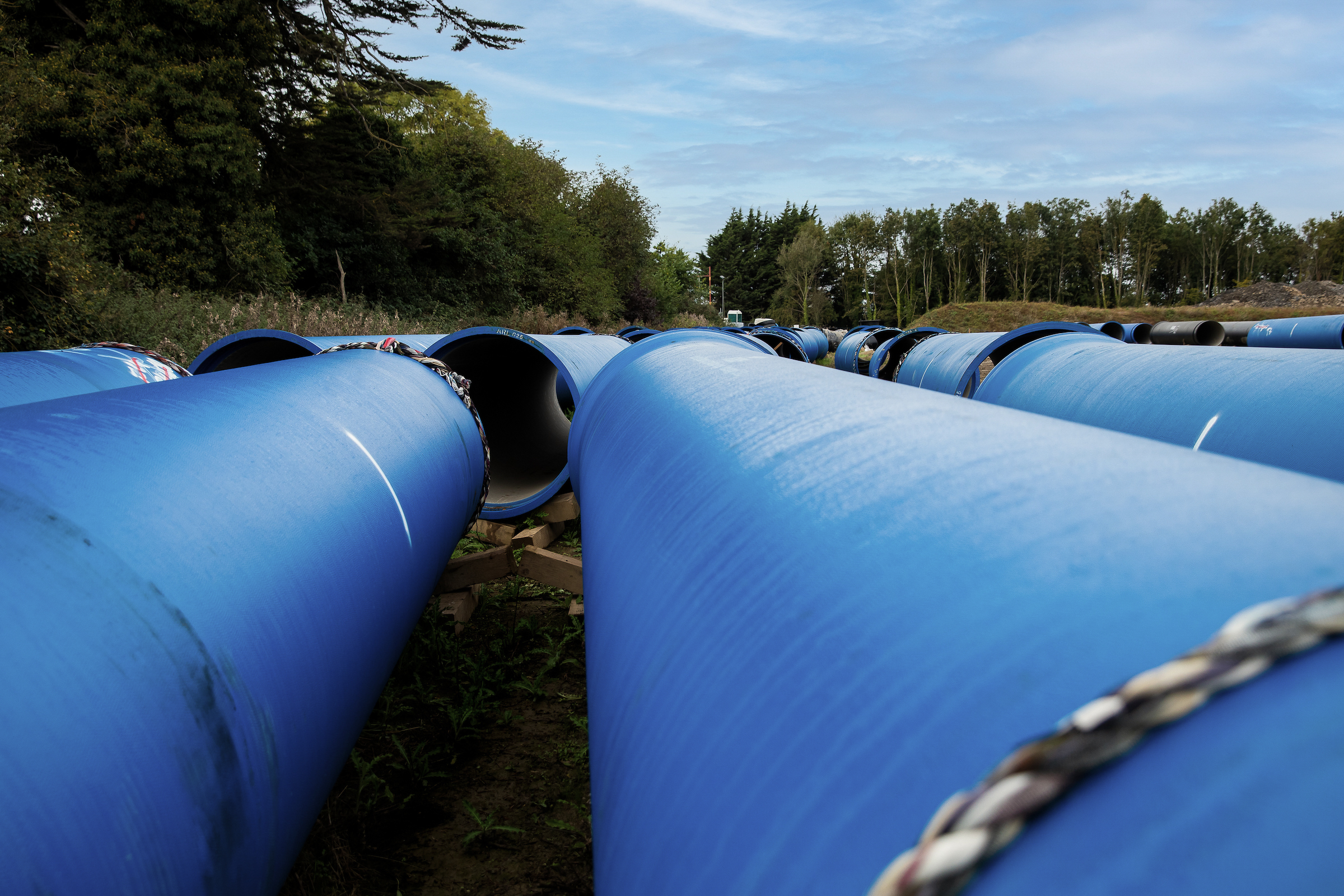A field with several large blue plastic pipes in Ballycoolin