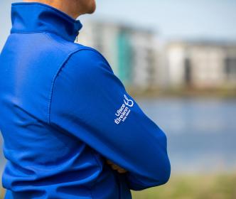 A side view of a man wearing a blue Uisce Éireann jacket